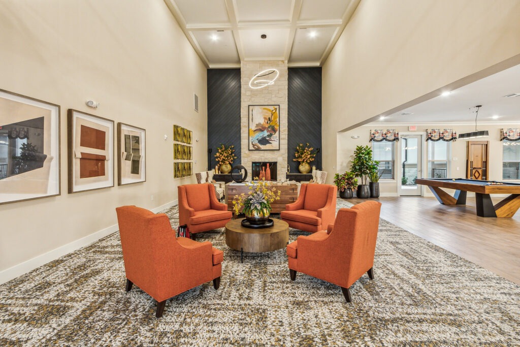 2310_Riverway_Dr_Conroe_TX_77304_USA-Foyer-IMG_4184 - Lakes at Woodhaven Interior living room with orange chairs and fireplace at The Lakes at Woodhaven Village, a retirement community near Huntsville, TX.