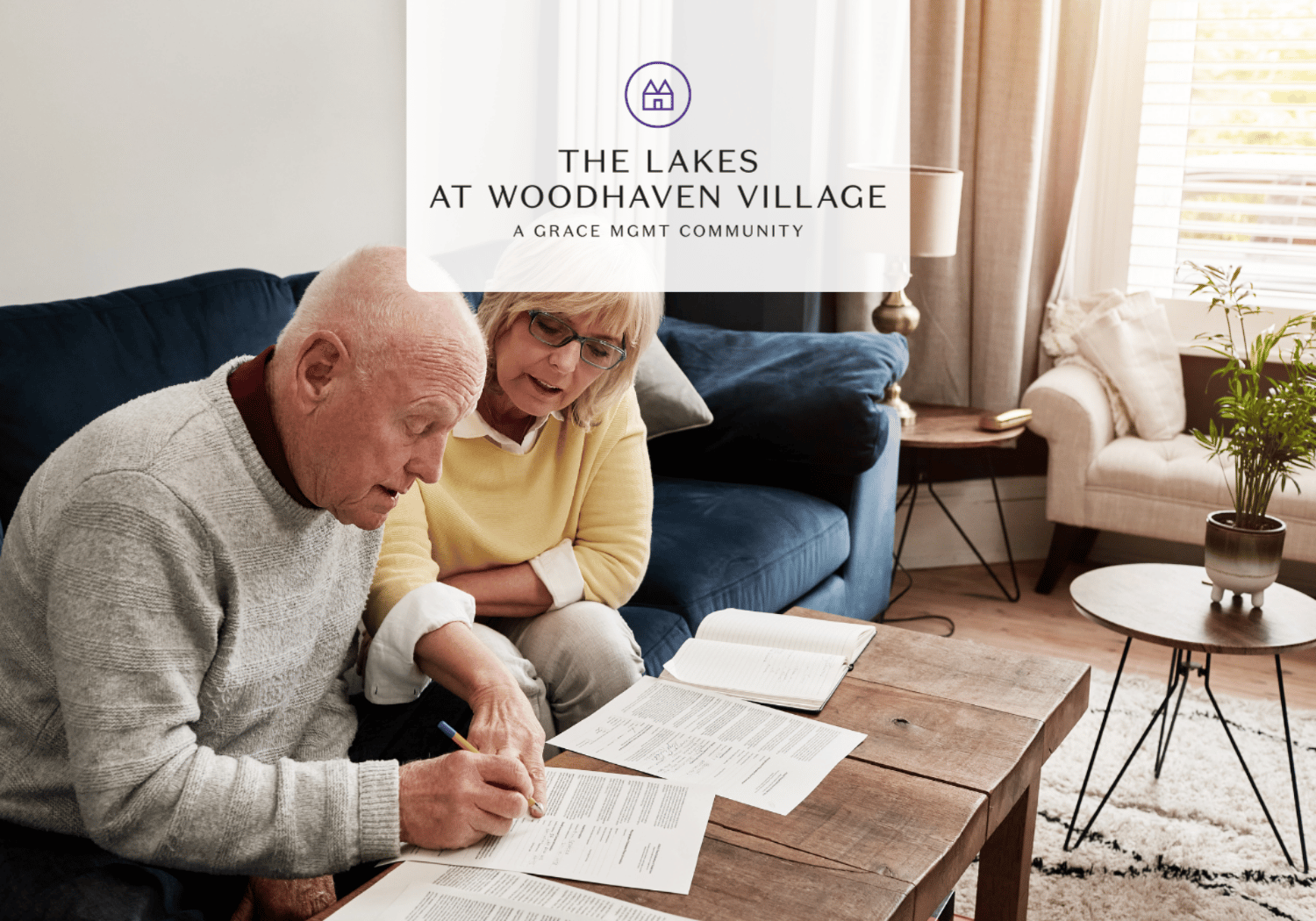 Elderly couple sitting on a living room couch, reviewing documents on a wooden coffee table.