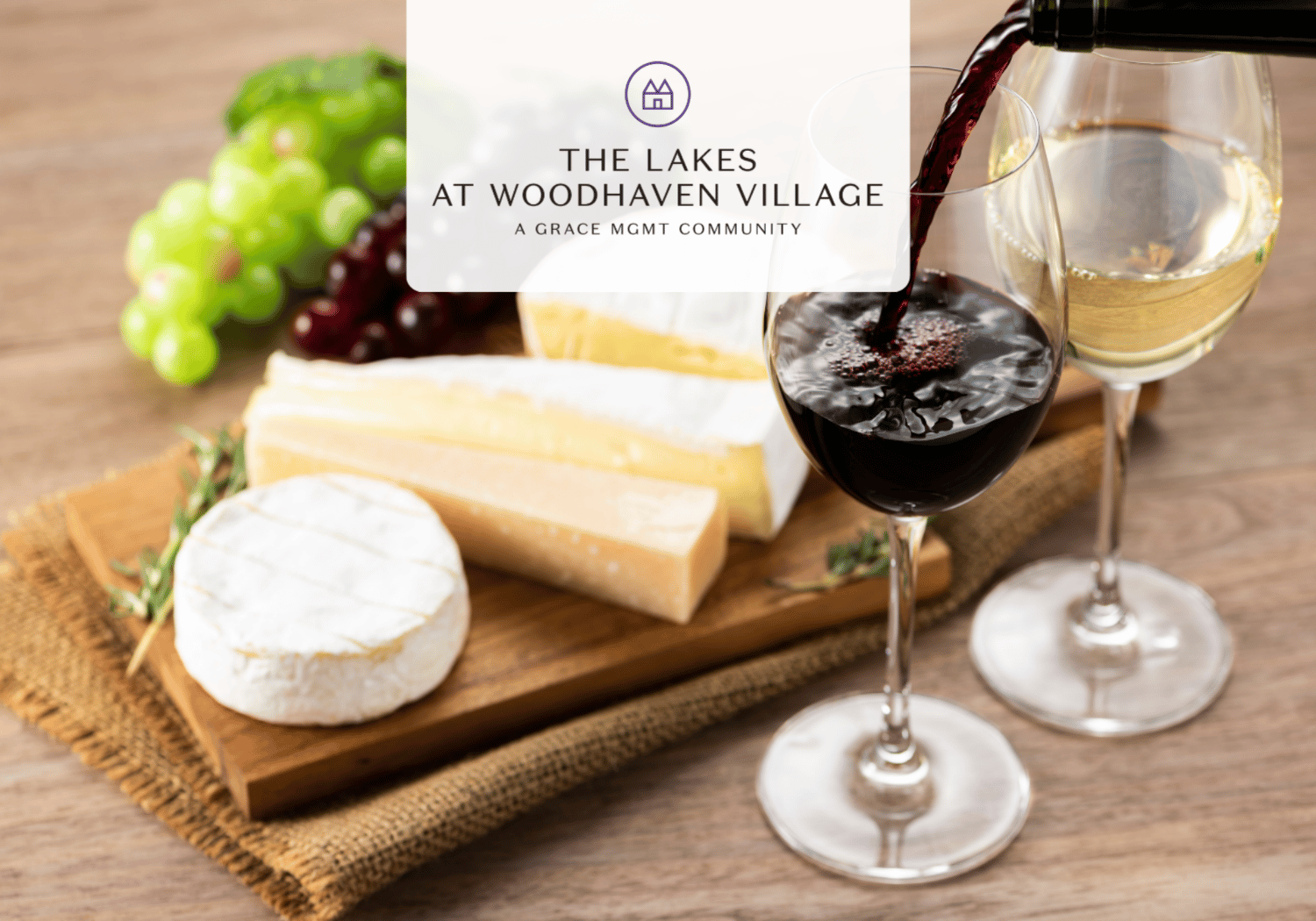 Wine glasses with red and white wine poured over a cheese board with grapes, branded with 'The Lakes at Woodhaven Village' logo.